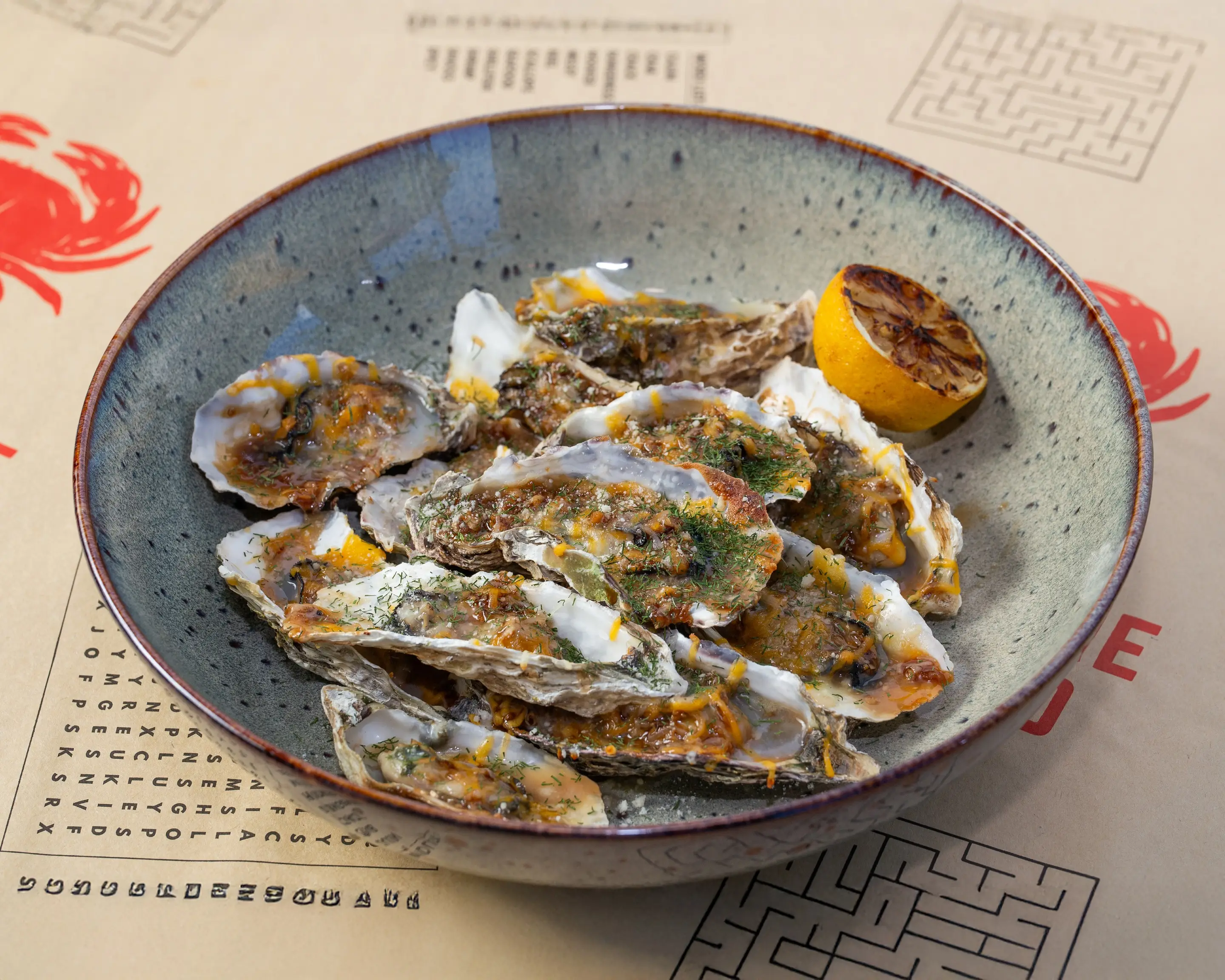 Oysters on the half shell in a speckled stone bowl, grilled under butter until the edges brown, scattered with dill and served with a charred lemon half.